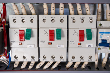 Three automatic motor protection switches with connected wires in the electrical Cabinet. The switches are arranged in a row. There is an adjustment of the current of the electric load.