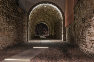An old illuminated historic tunnel in the old town and old stones on the walls