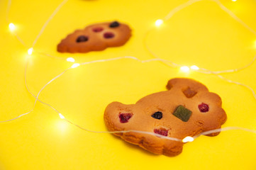 Side view of homemade cookies decorated with berries, raisins and colored candied fruits at yellow background