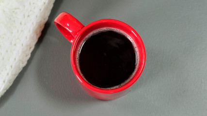 Person with mittens holding a cup of hot coffee. Close up