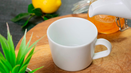 Pour tea in white cup on wooden board. Close up.