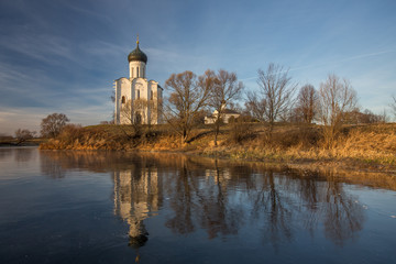 A beautiful temple on a background of bright golugobo sky stands on the shore of a lake is reflected in the ice at sunset