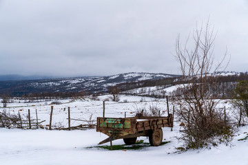 Mountain village and old wagon in snow