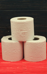 Three rolls of white toilet paper on wooden background with space for text. Deficit means of...