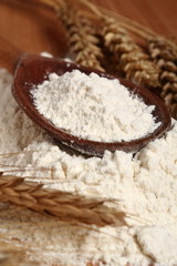 Wooden spoon with flour and wheat ears