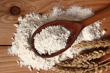 Fototapeta na wymiar Wooden spoon with flour and wheat ears