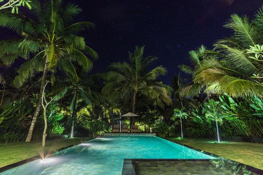 illuminated swimming pool at night in a tropical garden