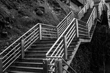 Black and white photograph detailing steel and wood stairs on the side of a cliff