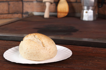 Whole wheat bread roll on paper plate at rural kitchen background
