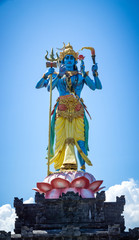blue shiva, hindu god statue standing up under a bright blue sky