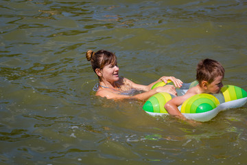 Boy with mother swimming with inflatable ring in the lake