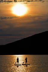 Fototapeta na wymiar Sup boarding couple on sunset