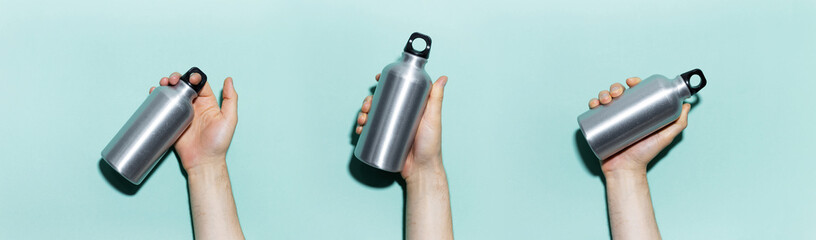 Collage of male hands holding reusable aluminum thermo water bottle on panoramic background of...