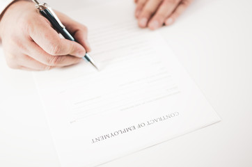Closeup of a businessman  signing an employment contract with a pen.
