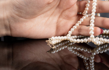 woman with pearl diamond necklace in hand