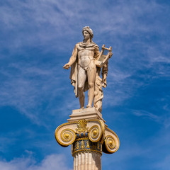 Obraz premium Apollo white marble statue on Ionian style column under blue sky with some clouds, Athens Greece