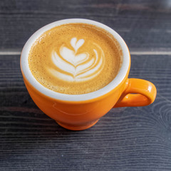 cappuccino orange cup on black wooden table top view