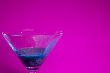 blue liquid in a cocktail martini glass on a pink background