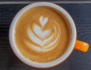 cappuccino orange cup on black wooden table top view