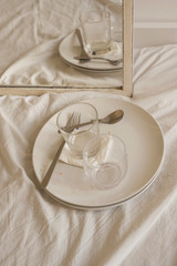 white interior detail of dirty dishes over bed sheet texture with mirror reflection vertical