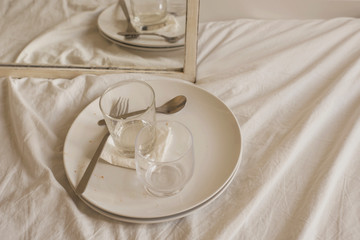 white interior detail of dirty dishes over bed sheet texture with mirror reflection horizontal