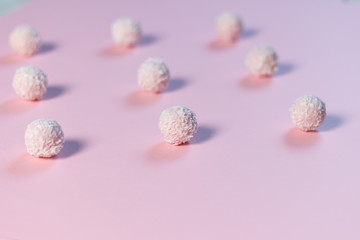 Sweet pink balls with coconut flakes on rose background as pattern