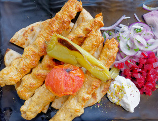 traditional kebab meat plate with tzatziki sauce, pepperoni, beetroot and pita bread, top view close up