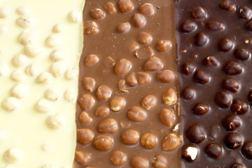 black, milk and white chocolate with nuts on a white background