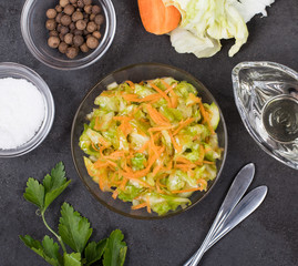Vegetable salad with cabbage and carrots in a bowl on a dark background top view