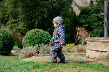 Cute toddler boy in hat eplore a garden in spring time
