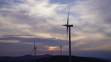Fototapeta na wymiar Wind turbines are generating power at sunset background. The concept of clean and renewable energy.