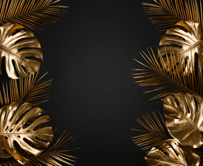 Shiny luxurious gold painted tropical monstera palm leaves border frame on abstract black background isolated