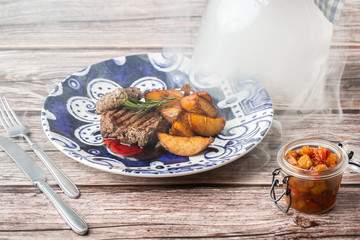 Grilled steak with baked golden potatoes on a wooden background. Top view. Delicious Recipe. Pork Fillet Cooked on Skillet for Dinner . Fried Juicy Meat Texture. Horizontal photo.