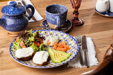 Poached eggs with salmon and avocado on sourdough toast isolated on wooden background. Homemade food. Tasty breakfast. Selective focus. Top view.