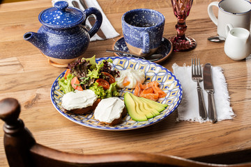 Poached eggs with salmon and avocado on sourdough toast isolated on wooden background. Homemade food. Tasty breakfast. Selective focus. Top view.