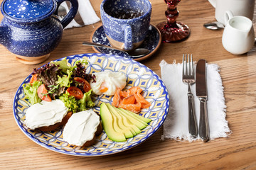 Poached eggs with salmon and avocado on sourdough toast isolated on wooden background. Homemade food. Tasty breakfast. Selective focus. Top view.
