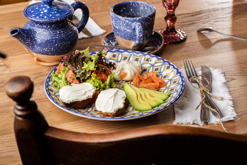 Fototapeta na wymiar Poached eggs with salmon and avocado on sourdough toast isolated on wooden background. Homemade food. Tasty breakfast. Selective focus. Top view.