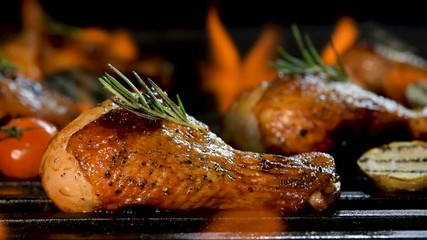 Close up grill roast bbq chicken leg with addition herbs and spices on the flaming grill .