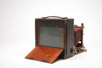 View from back of Vintage, large-format, 4x5, glass negative, view camera. Red leather bellows partially extended. Isolated shot on white background. Showing back open and ground glass viewer.