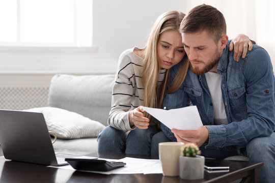 Upset Couple Reading Financial Statement From Bank At Home