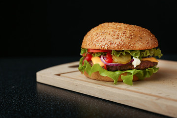 classic burger on board on black background
