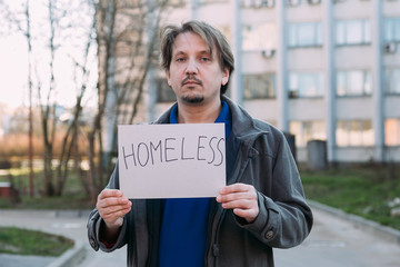 A homeless person holds a sign , asks for work, and seeks help. The concept of poverty and homelessness