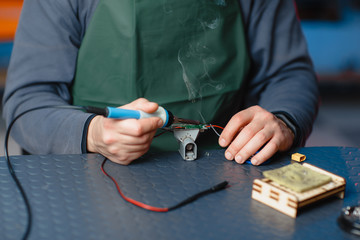 Close-up photo of male engineer or technician repair soldering drone details.