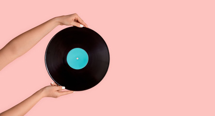 Young woman holding gramophone record on pink background, closeup. Copy space. Panorama