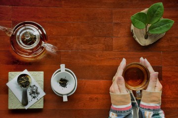 Fototapeta na wymiar Tea set with tea cup in lady hand are on wooden table