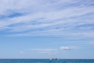 landscape with sea, beach, blue sky and  small white ship in distance, sunny day in Mediterranean