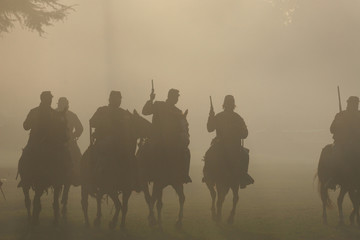 Group of silhouetted Soldiers on Horseback with Guns in the air moving forward in the smokey haze toward the battle in the American Civil War - obrazy, fototapety, plakaty