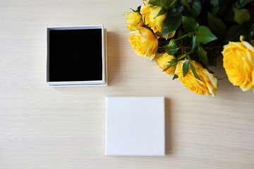 Top view for presentation. Empty box for jewelry, gift. Place for logo, sale text. Yellow roses bouquet on the table.