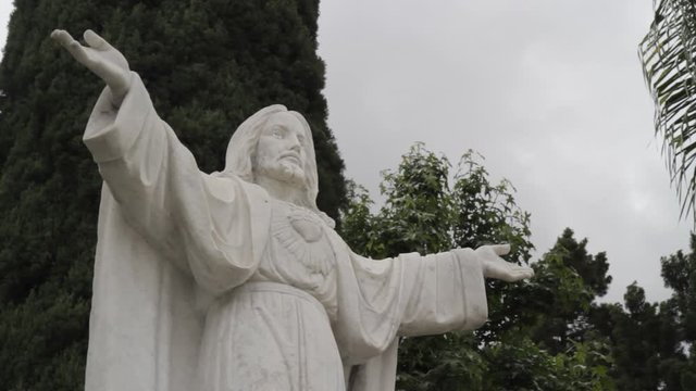 Jesus Christ Statue Outside of Church Garden with Clouds and Trees in background_Slider Pan HD