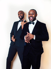 two afro-american businessmen in black suits emotional posing, gesturing, smiling. wearing bow-ties entertaiment stuff